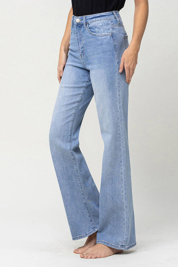 left view with leg extended on 90's vintage super high rise flare jeans with comfort stretch denim, full length, and flare legs. Front rise: 11.5 inches, inseam: 32 inches, leg opening: 20 inches. Model is 5'9'' wearing size 26.