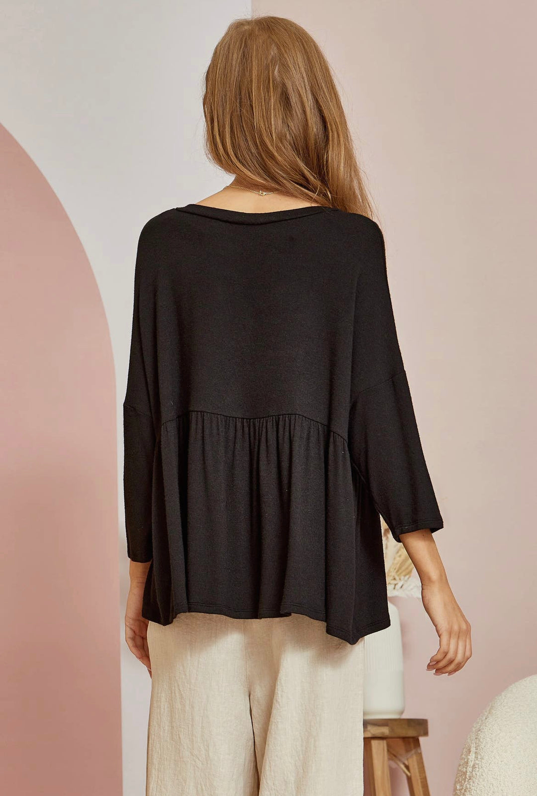 back view of Black babydoll tee with 3/4 sleeves. Made from a blend of 65% polyester, 32% rayon, and 3% spandex. A versatile closet staple