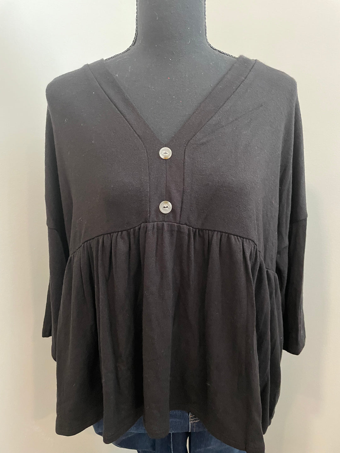 mannequin view of Black babydoll tee with 3/4 sleeves. Made from a blend of 65% polyester, 32% rayon, and 3% spandex. A versatile closet staple