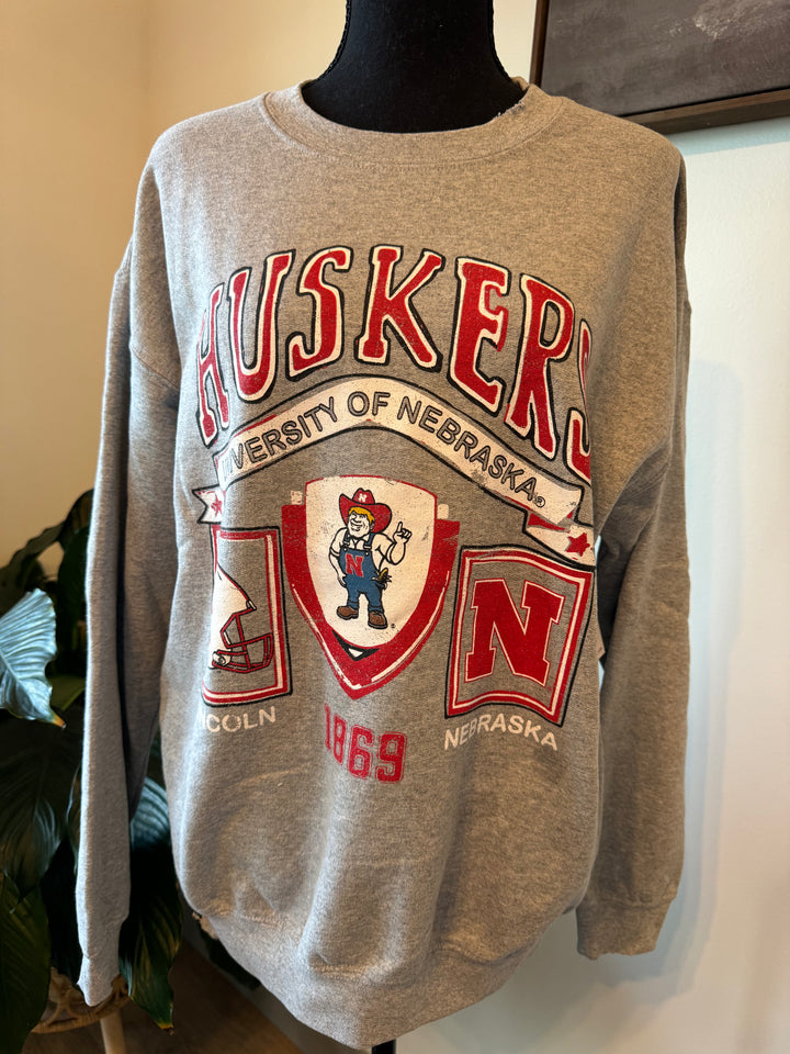 mannequin view of Nebraska Huskers Prep Patch Gray Thrifted Sweatshirt, 50/50 cotton/poly blend, meaningfully distressed and unique. Unisex fit, officially licensed.