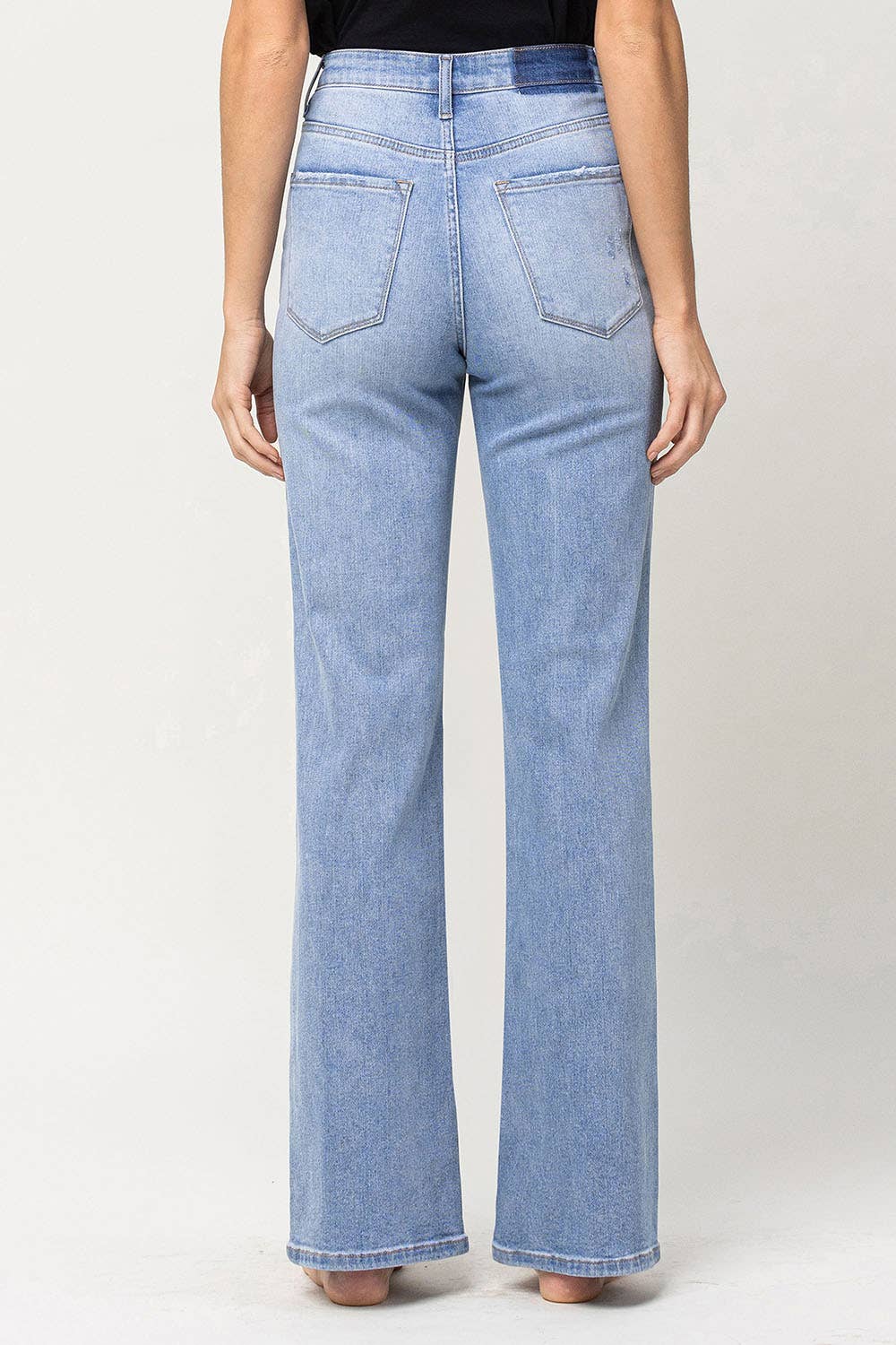back view of 90's vintage super high rise flare jeans with comfort stretch denim, full length, and flare legs. Front rise: 11.5 inches, inseam: 32 inches, leg opening: 20 inches. Model is 5'9'' wearing size 26.