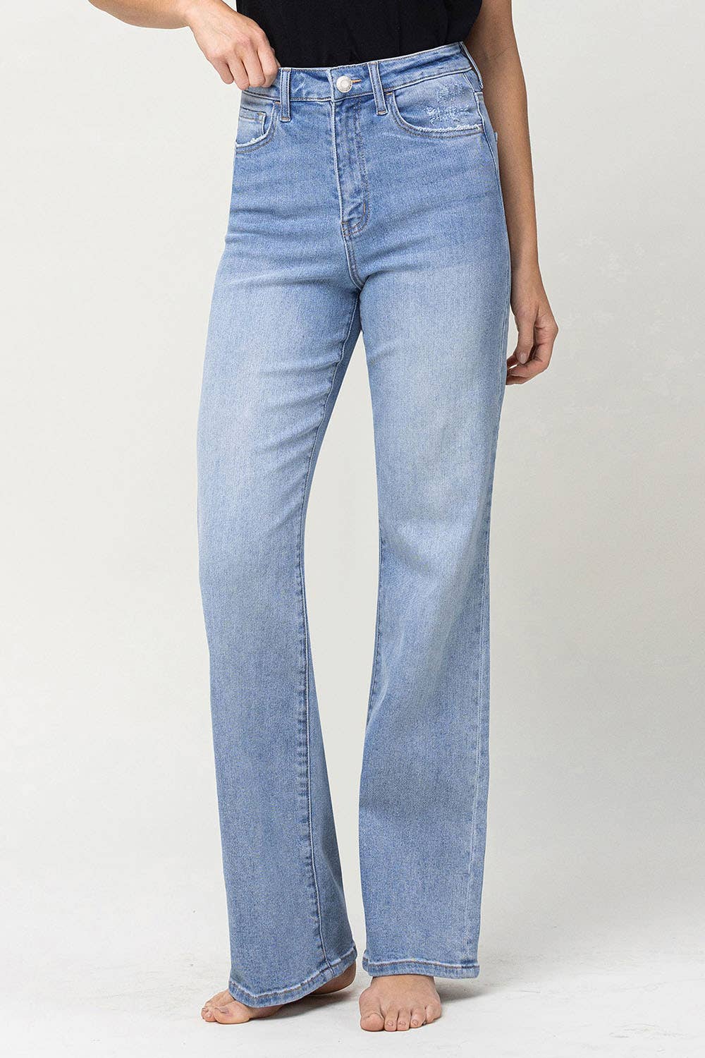 slight left side view of 90's vintage super high rise flare jeans with comfort stretch denim, full length, and flare legs. Front rise: 11.5 inches, inseam: 32 inches, leg opening: 20 inches. Model is 5'9'' wearing size 26.