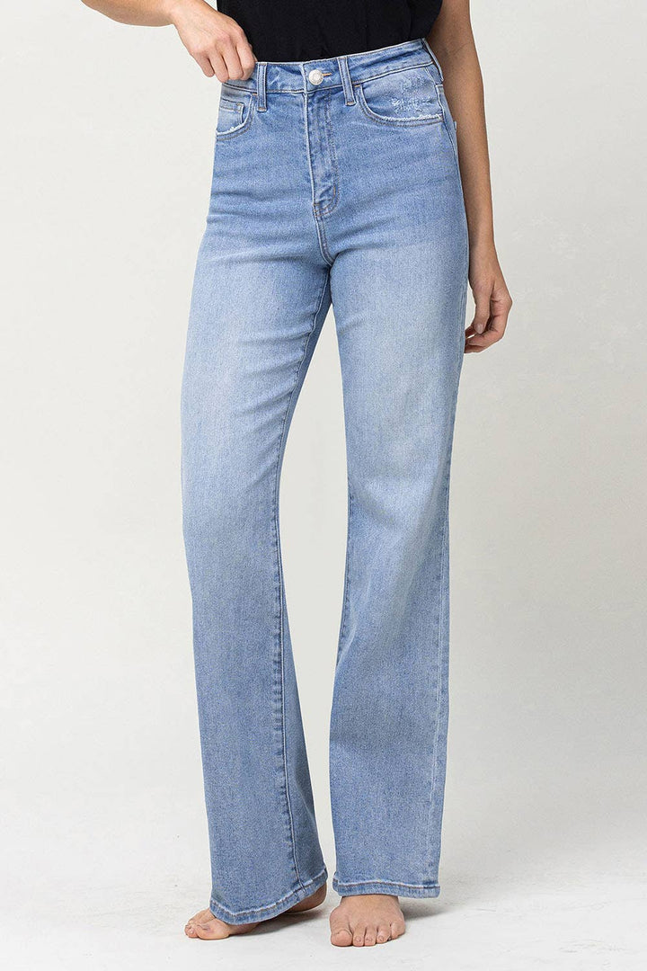 slight left side view of 90's vintage super high rise flare jeans with comfort stretch denim, full length, and flare legs. Front rise: 11.5 inches, inseam: 32 inches, leg opening: 20 inches. Model is 5'9'' wearing size 26.