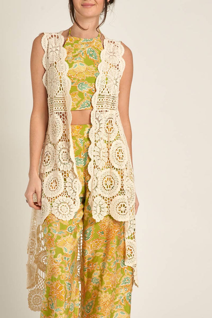 styled view of Elevate your style with our Sleeveless High-Low Crochet Cardigan made from 100% cotton. This versatile piece features a high-low design for a chic look.