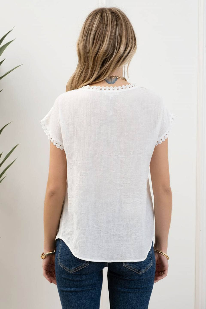 back view of Whitney Floral Embroidery Blouse with a round neckline, short sleeves, and scallop lace trim. Made from 86% rayon and 14% nylon with a contrast of 100% polyester.