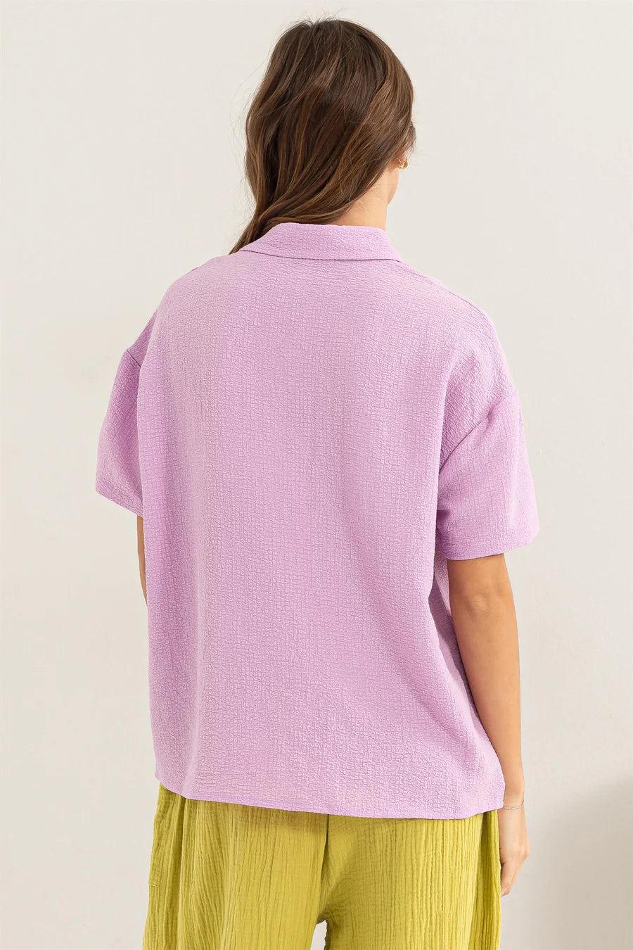 back view of Lavender Haze Button Down Shirt - Textured fabric with point collar, drop shoulders, short sleeves, and a relaxed fit. Tuck-in option for a polished look.