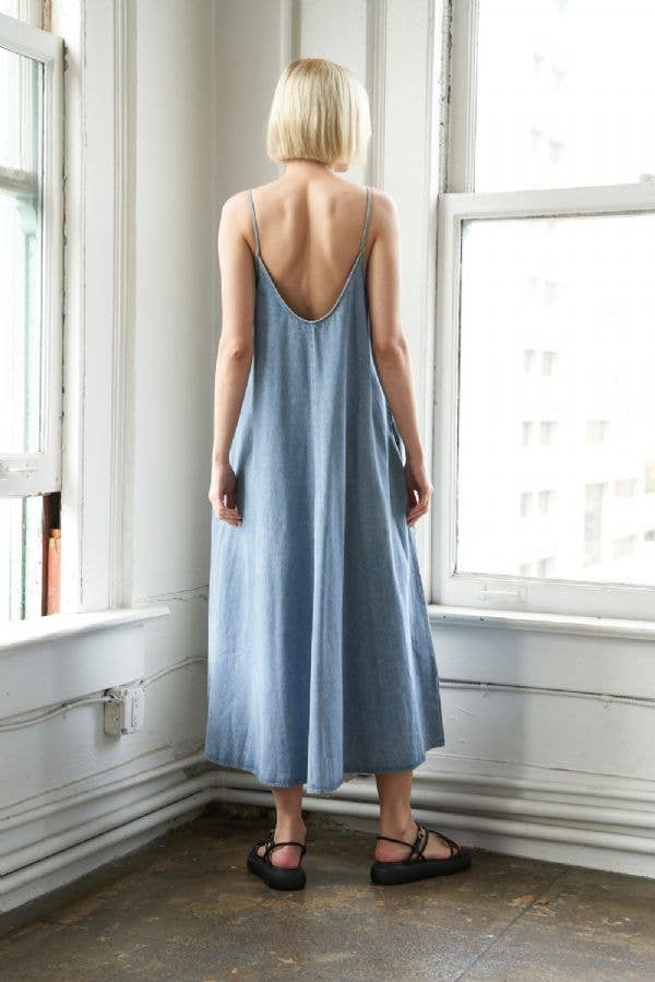 back view of Washed denim midi dress with side pockets and straps. Made from 85% cotton, 10% polyester, and 5% viscose. Approx. length 52 inches. 