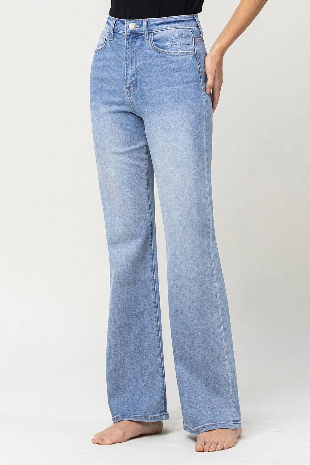 left side view of 90's vintage super high rise flare jeans with comfort stretch denim, full length, and flare legs. Front rise: 11.5 inches, inseam: 32 inches, leg opening: 20 inches. Model is 5'9'' wearing size 26.
