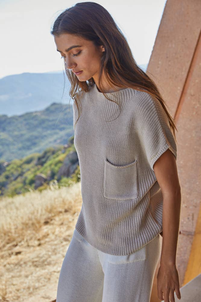 slight side view of Women's cotton knit sleeveless mock neck sweater top with front pocket in beige