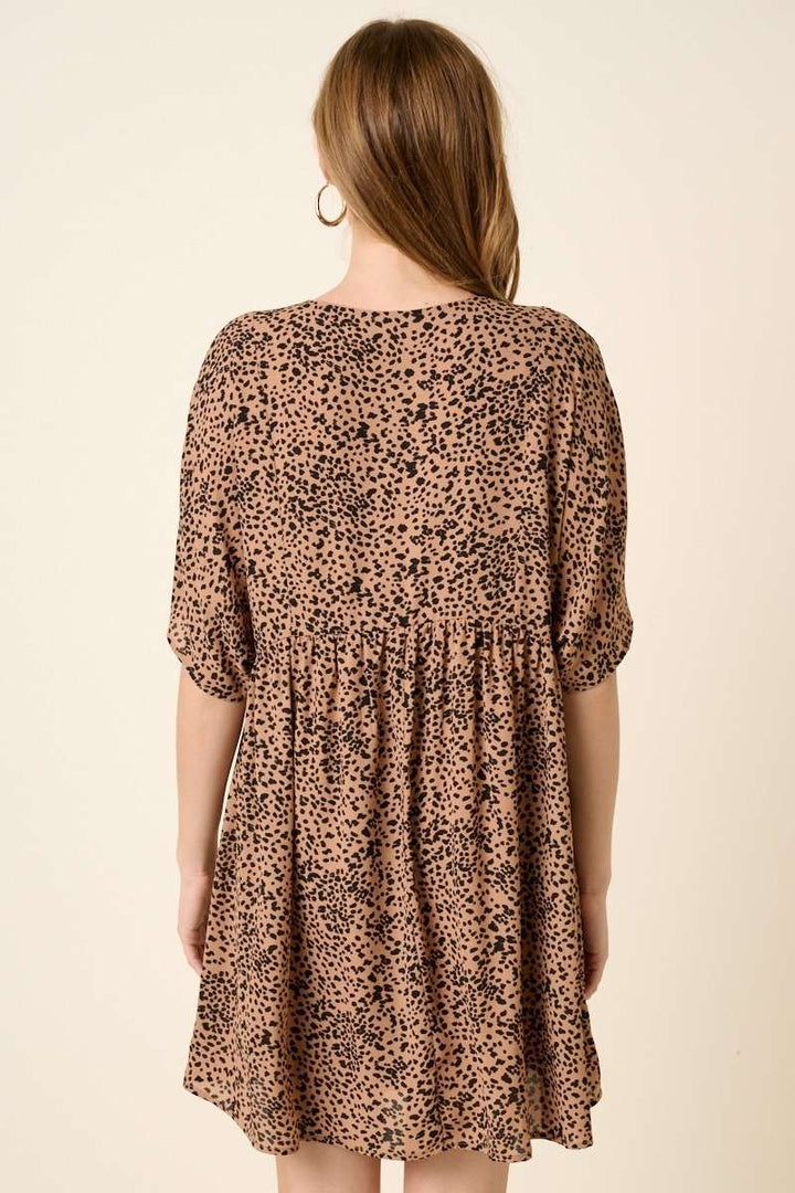 back view of Abstract leopard print mini dress with a V-neckline, dolman sleeves, babydoll body, loose fit, and pocket detail. Body lined.