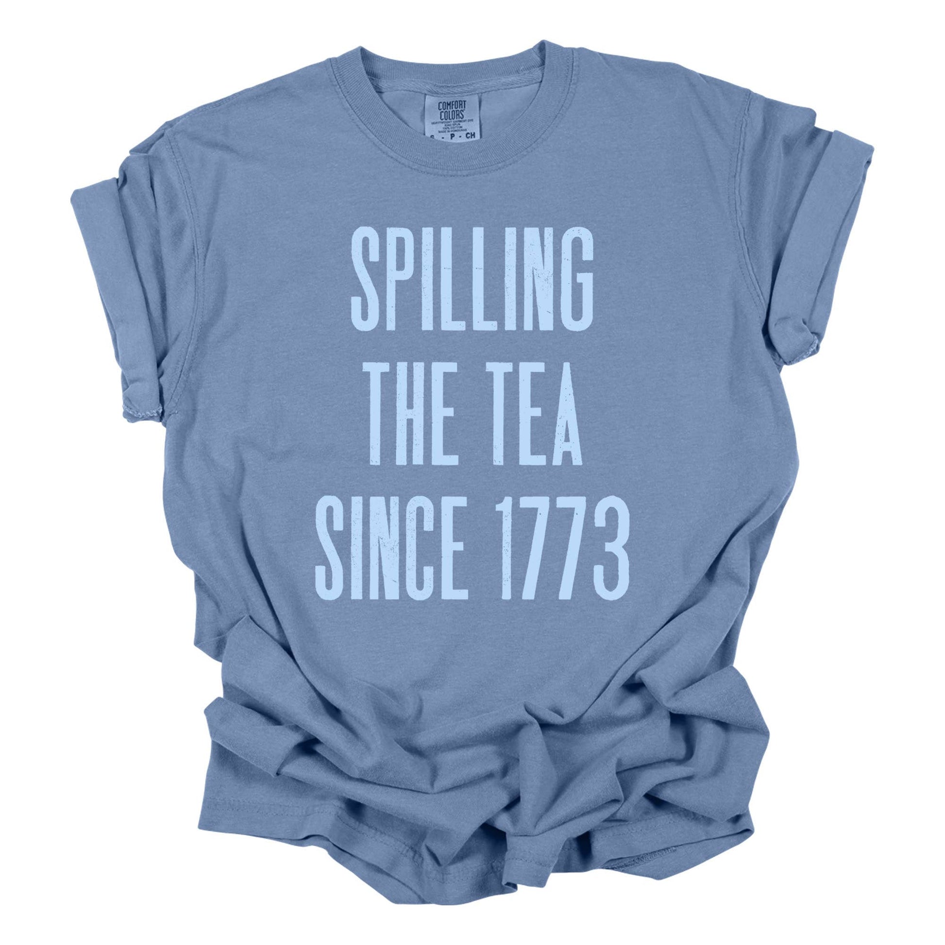 Spilling the Tea Since 1773' Tee in washed denim and white, made from 100% cotton with a relaxed fit. Features screen-printed graphics and a crew neck. Available in navy Bella Canvas (60/40 cotton-poly blend).