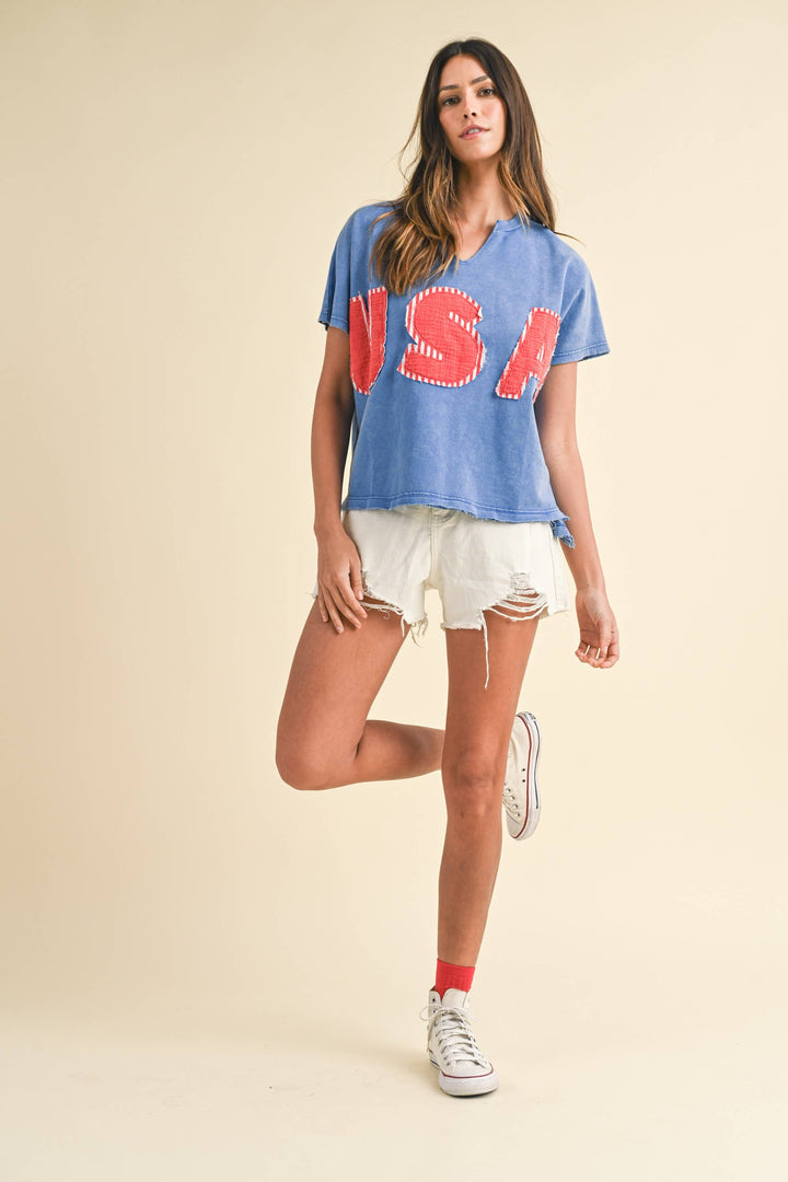 zoomed out view of Mineral Washed USA Patched Knit Top with mixed fabric lettering patch, lightweight French terry, notched neckline, short dolman sleeves, raw edge details, and loose fit.