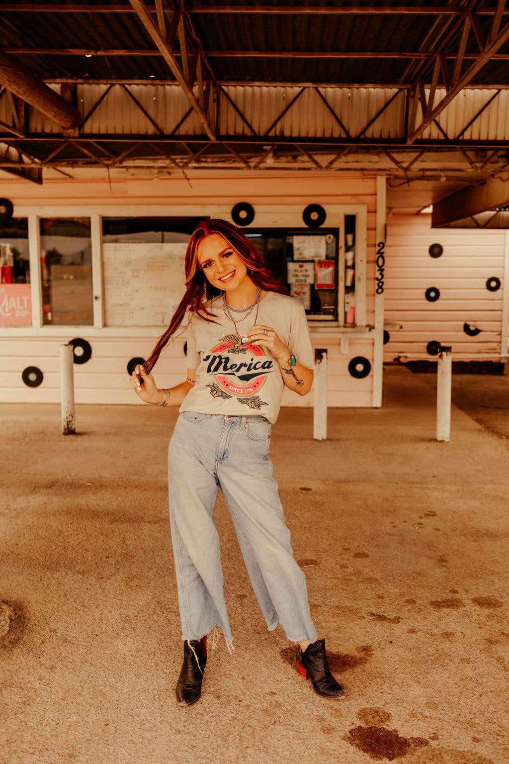 styled with bell bottom jeans and Merica Beer t-shirt with faded print, showcasing patriotic style. Made in the USA. Screenprinted or sublimated on grey Next Level. Unisex tee.