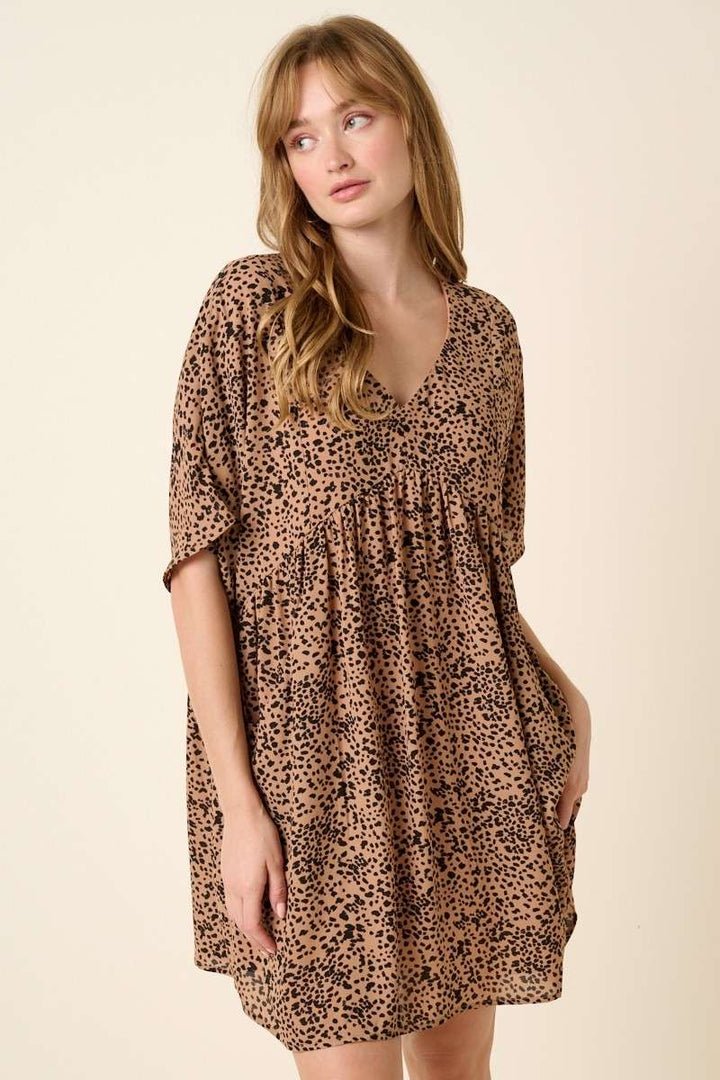slight right side view of Abstract leopard print mini dress with a V-neckline, dolman sleeves, babydoll body, loose fit, and pocket detail. Body lined.