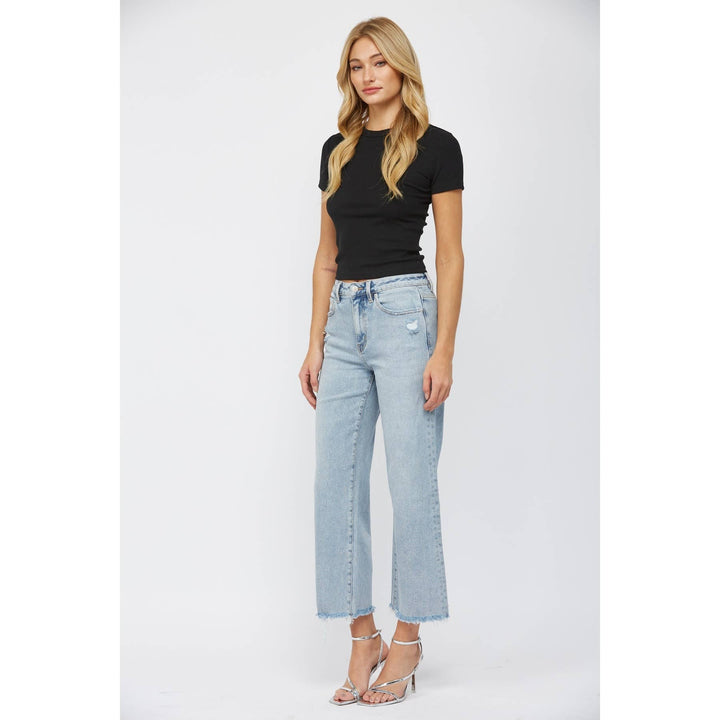 slight left side vew of High-rise ankle wide-leg jeans in light wash with minimal distressing. Made from 98% cotton and 2% spandex.