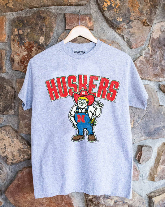 Nebraska Huskers Cartoon Mascot gray thrifted tee made from 100% preshrunk cotton, showcasing unique colors and distressing.