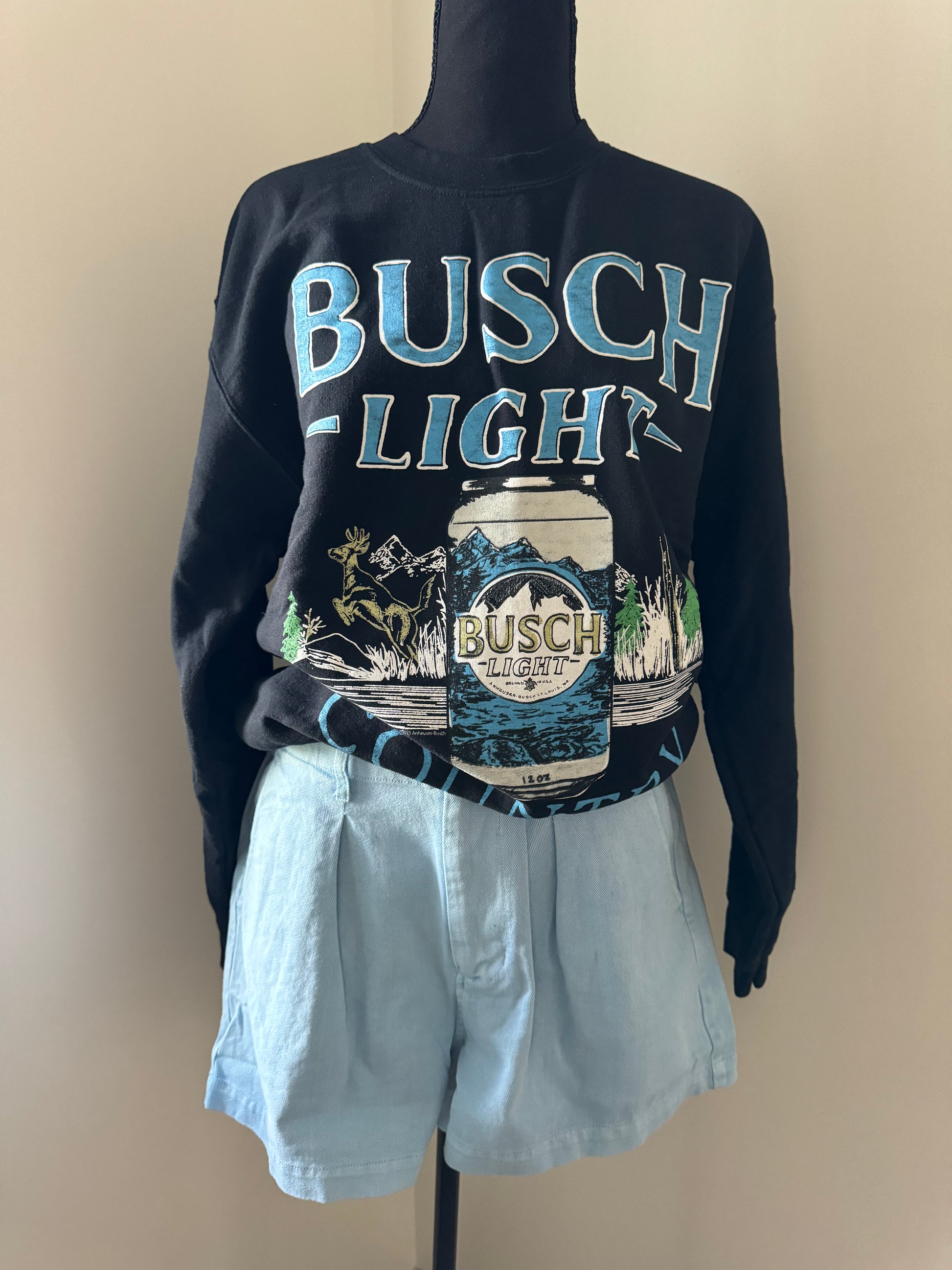 mannequin view of Busch Light Country crewneck sweatshirt with Junkfood design, featuring hunting, fishing, and loving every day slogan. Unisex.