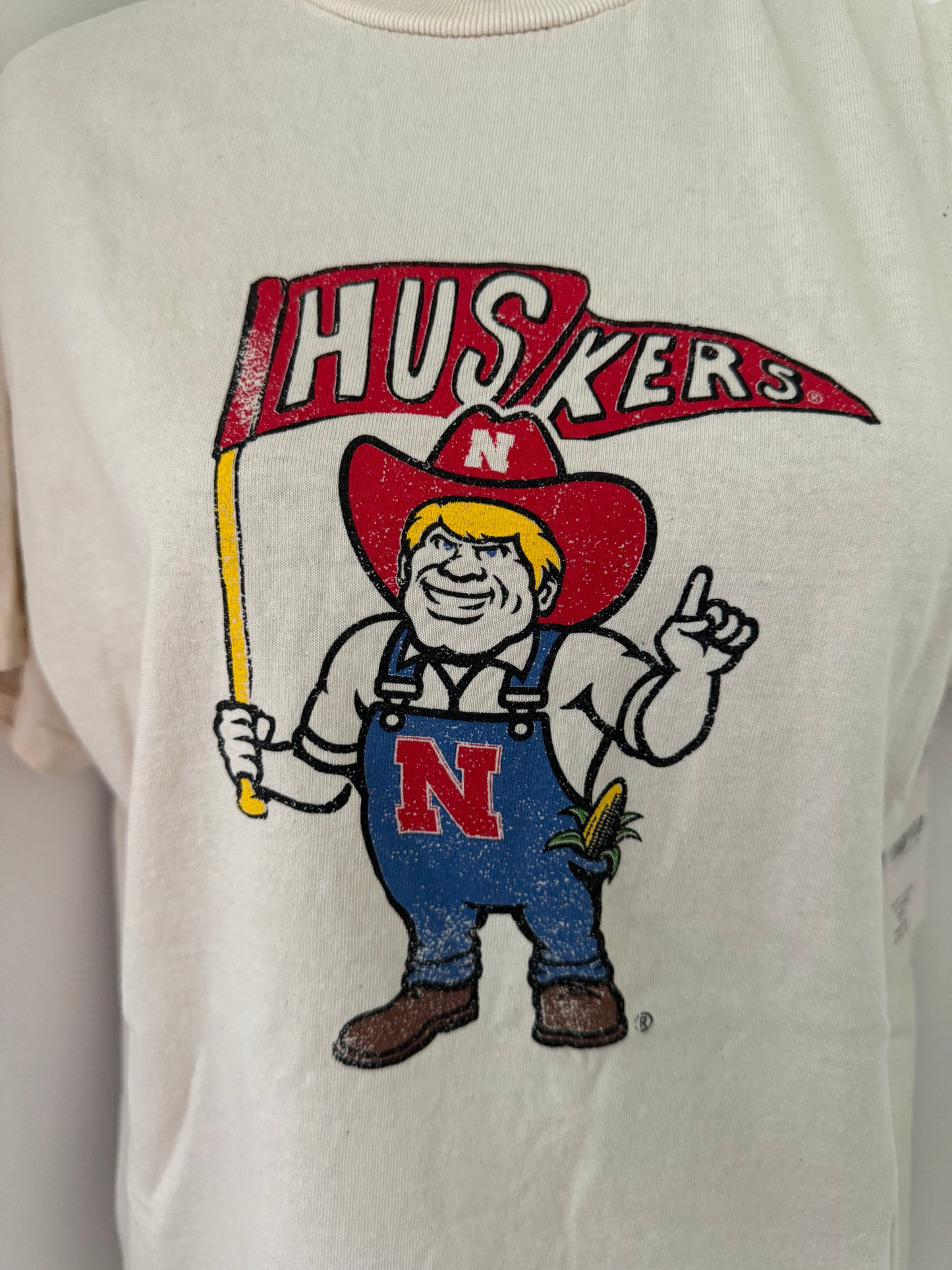 Zoomed in view of Nebraska Huskers Mascot Flag Game Day Tee - Vintage-inspired 100% preshrunk cotton shirt with unique distressing, unisex fit, officially licensed, pairs well with vintage denim