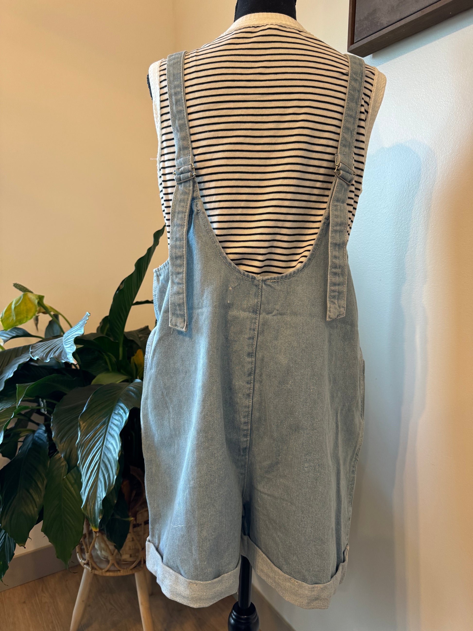 back view on mannequin wearing Cotton Denim Seam Detail Romper with adjustable straps and front pockets, made of 100% cotton. Available for pre-order with color variations possible due to lighting and monitor differences.