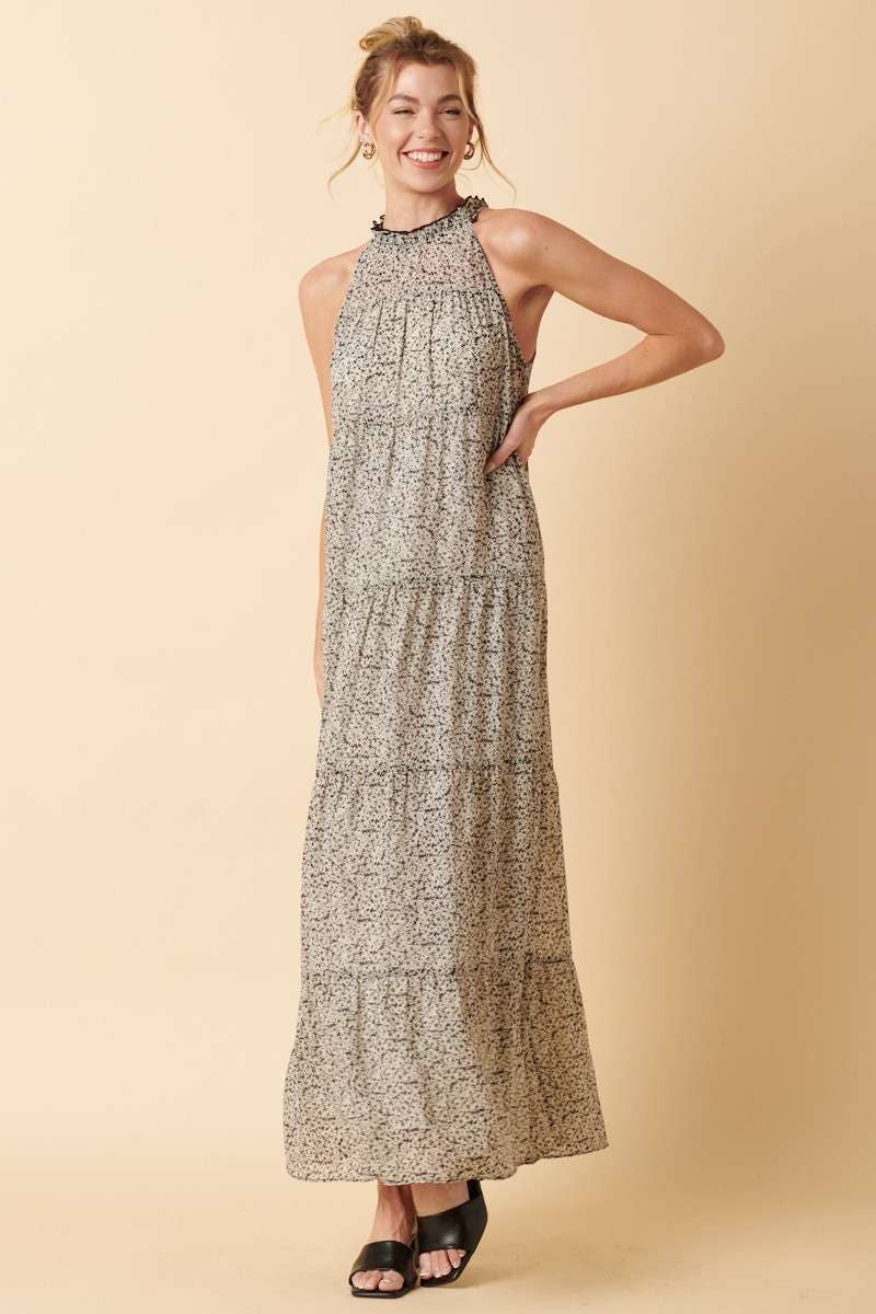 styled view of Sally Flower Halter Maxi Dress with flower print on chiffon fabric, ruffle mock neck, tie back, sleeveless halter design, and tiered detail. Maxi length for an elegant silhouette.