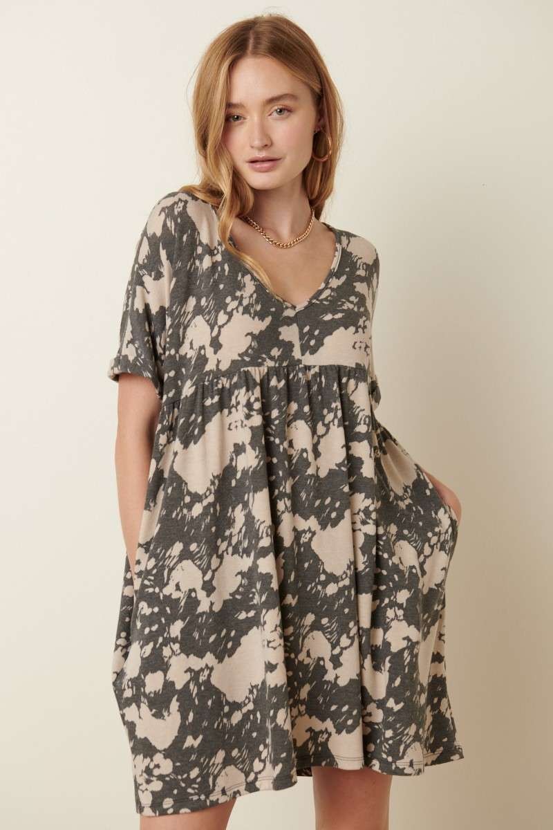 Front view of Abstract print babydoll dress with a deep V-neck, cuffed sleeves, and side pockets. Made from 63% polyester, 34% rayon, and 3% spandex. Model is 5'9'' wearing size small.