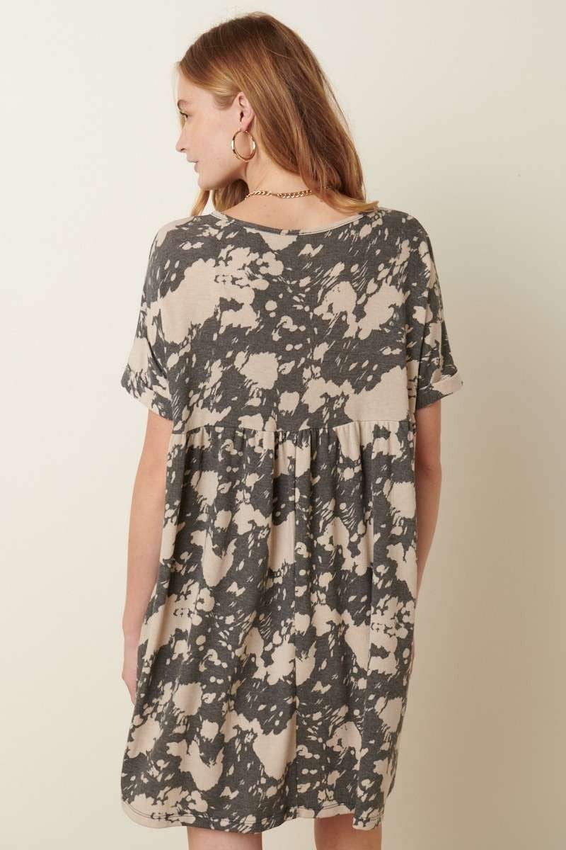 Abstract print babydoll dress with a deep V-neck, cuffed sleeves, and side pockets. Made from 63% polyester, 34% rayon, and 3% spandex. Model is 5'9'' wearing size small.
