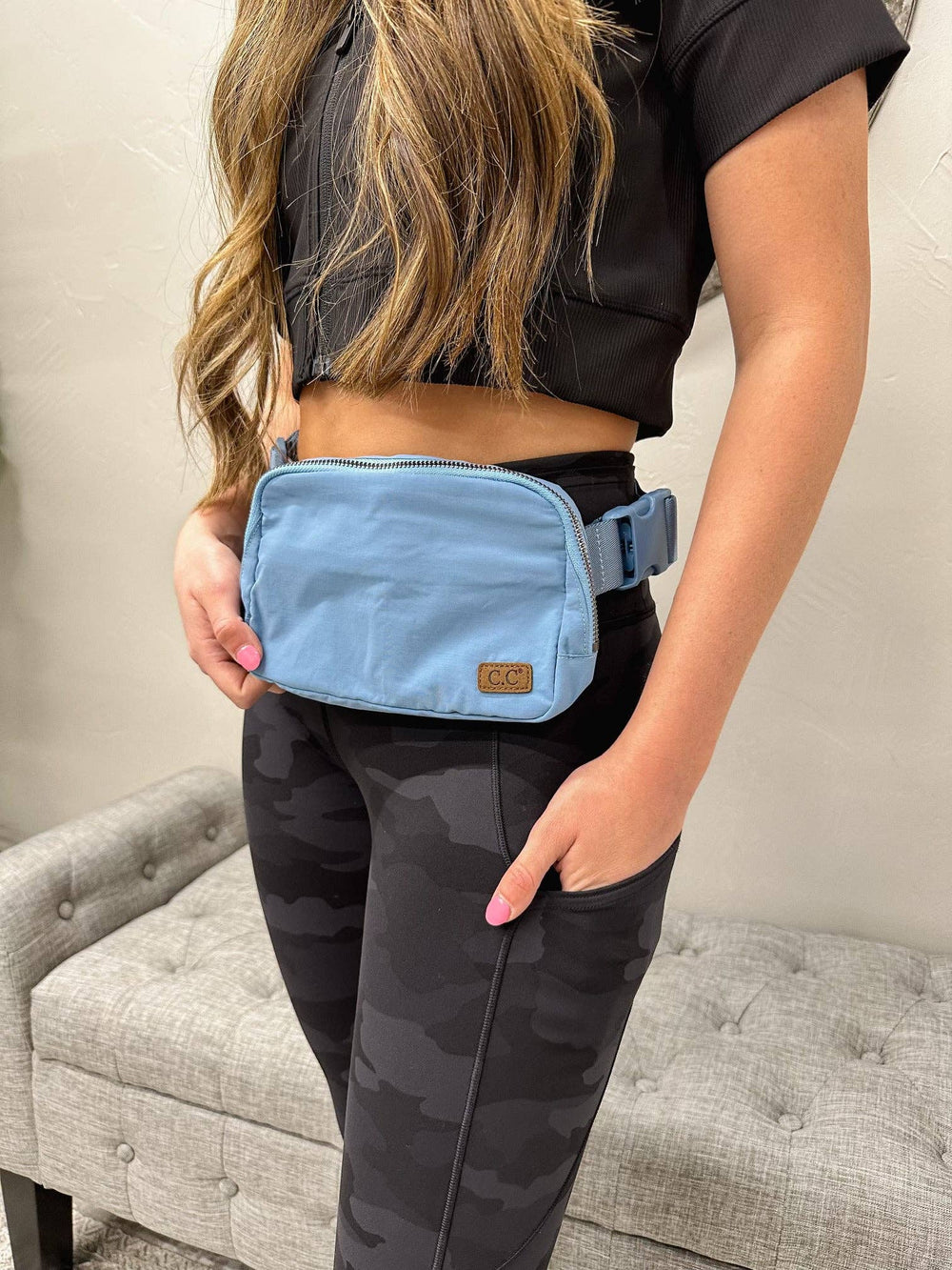 model wearing Steel Blue C.C Belt Bags - Stylish and functional belt bags in a steel blue color. Features include a zippered pouch with elasticized compartments, adjustable strap, and waterproof design