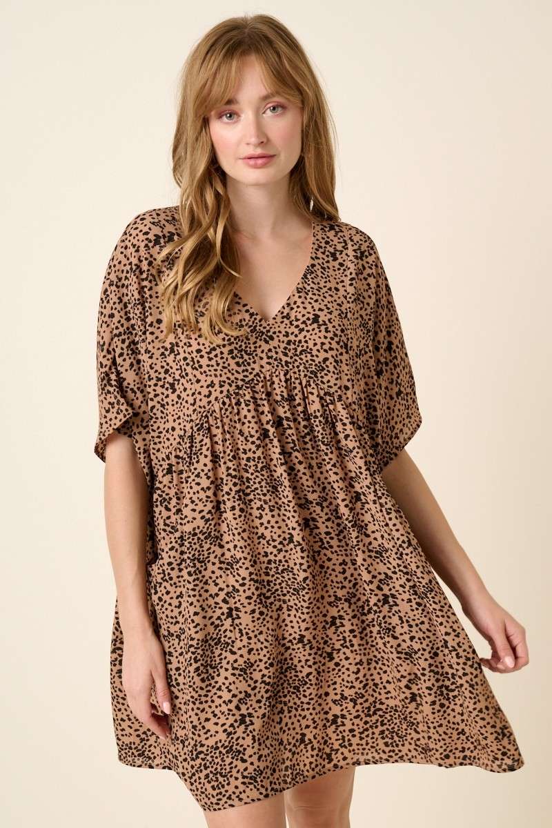 Abstract leopard print mini dress with a V-neckline, dolman sleeves, babydoll body, loose fit, and pocket detail. Body lined.