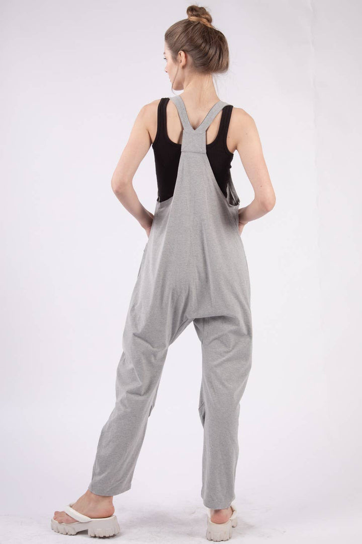 back view of Casual loose fit solid knit baggy jumpsuit with a deep V-neck, sleeveless design, raw edge detail, and side pockets. 