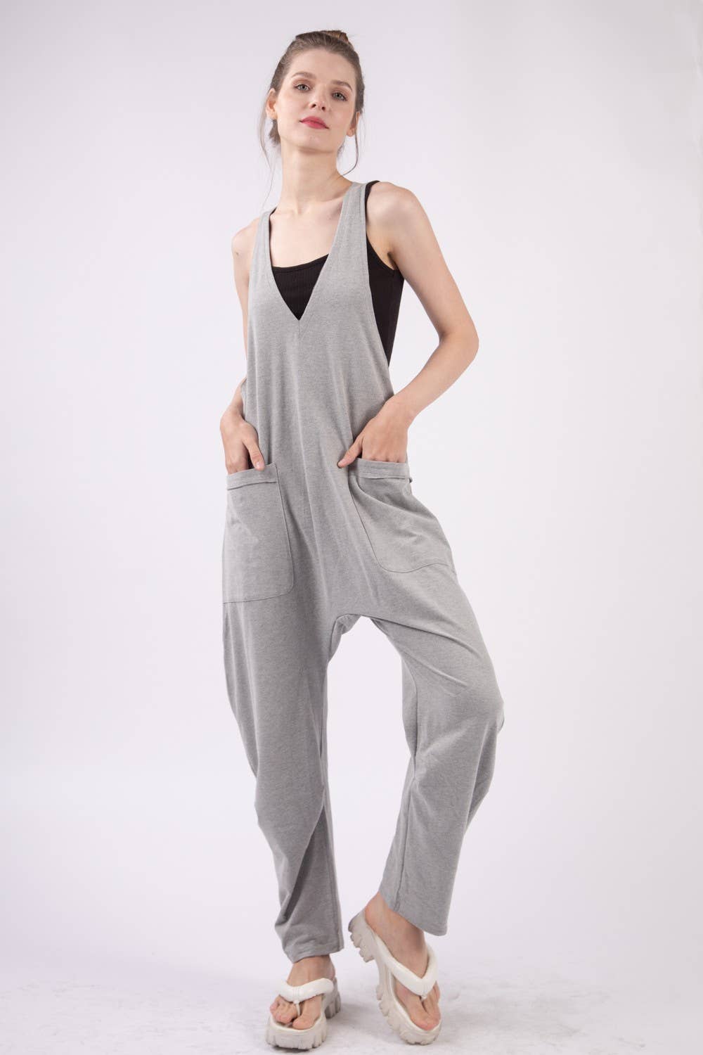 slight right view of Casual loose fit solid knit baggy jumpsuit with a deep V-neck, sleeveless design, raw edge detail, and side pockets. 