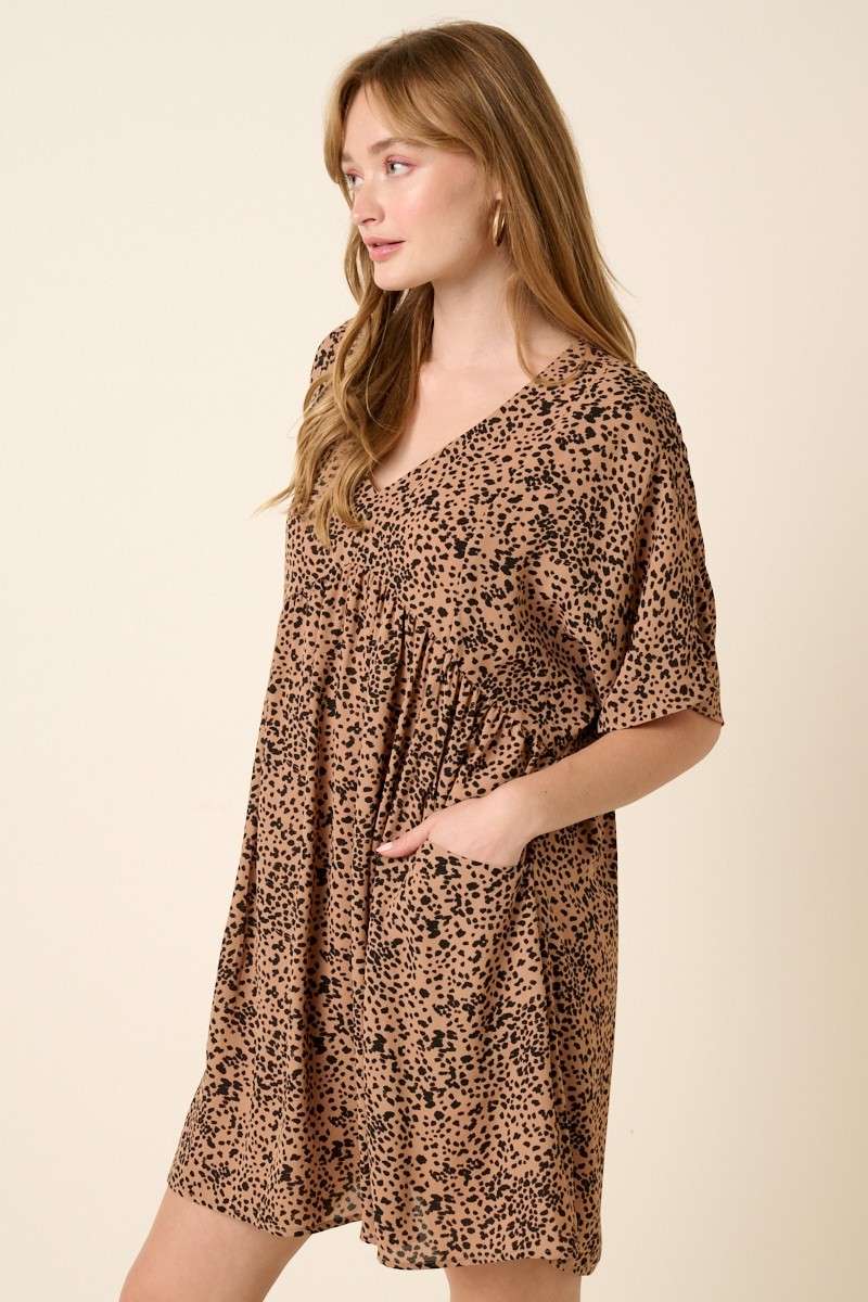Left side view of Abstract leopard print mini dress with a V-neckline, dolman sleeves, babydoll body, loose fit, and pocket detail. Body lined.