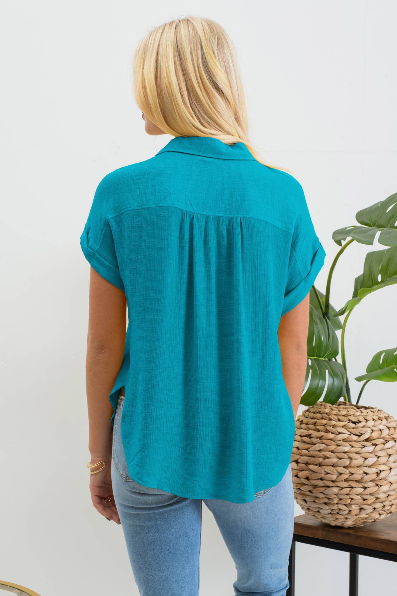 back view of Mid Button Down Woven Top with pointed collar, front functional buttons, folded cuff short sleeves, back yoke, and shirring detail. Made of 80% rayon and 20% nylon.