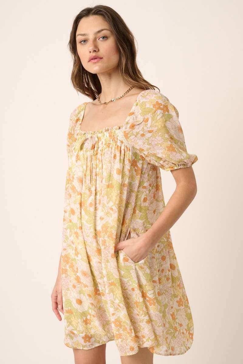 hand in pocket view of Vintage Flower Print Mini Dress with square neck, short puff sleeves, and tie detail on top. Made from chiffon woven fabric and fully lined. Model is 5'9" wearing size Small.