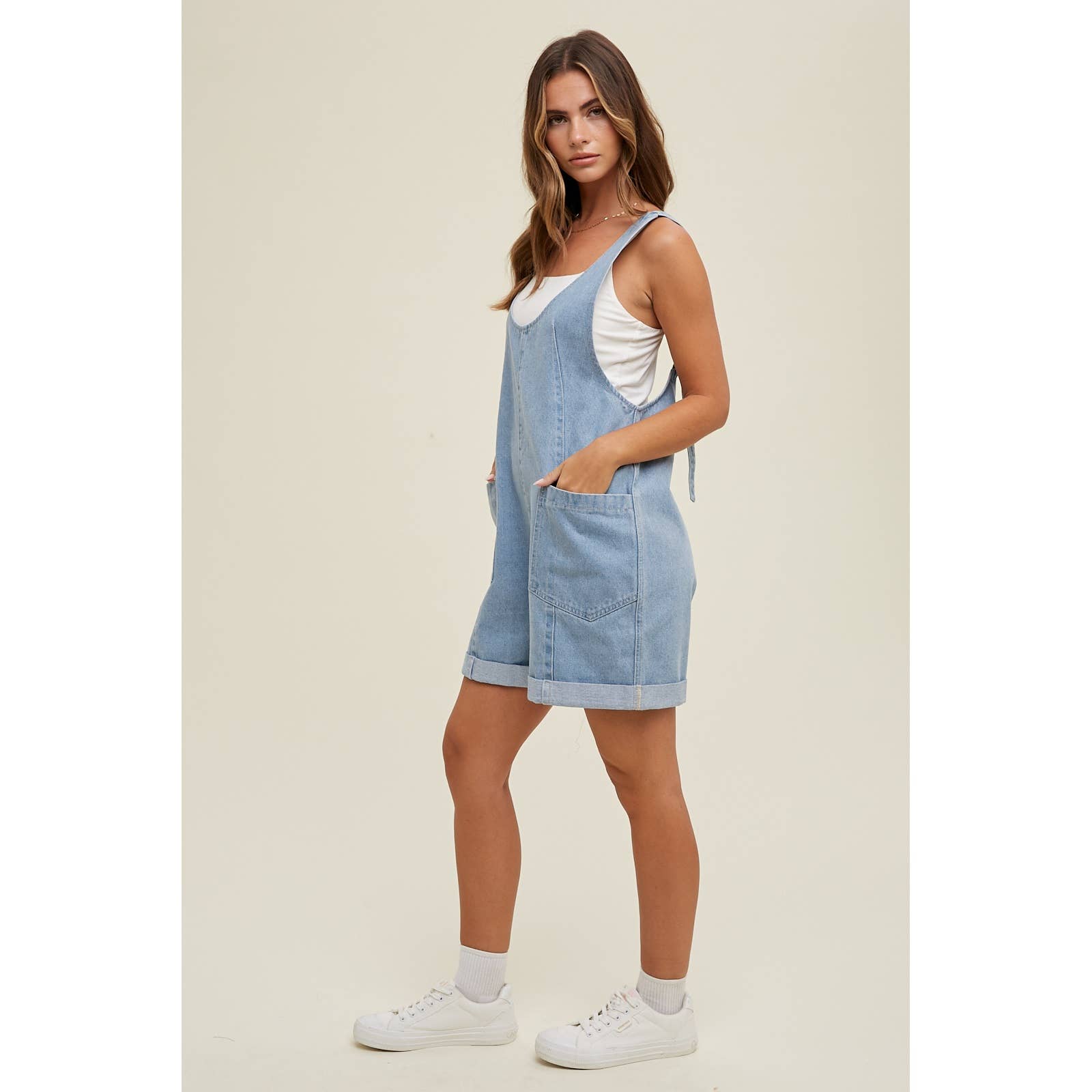 side view of Cotton Denim Seam Detail Romper with adjustable straps and front pockets, made of 100% cotton. Available for pre-order with color variations possible due to lighting and monitor differences.