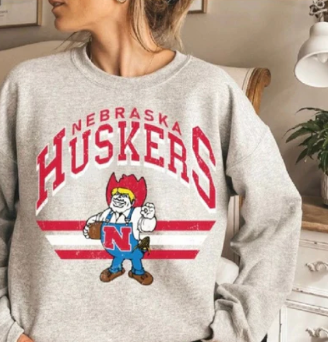 Nebraska Huskers Football crewneck sweatshirt in a 50/50 cotton-poly blend. Features pre-shrunk fabric, classic fit, air-jet spun yarn for softness, and double-needle stitching for durability. Ideal for staying warm in colder months.