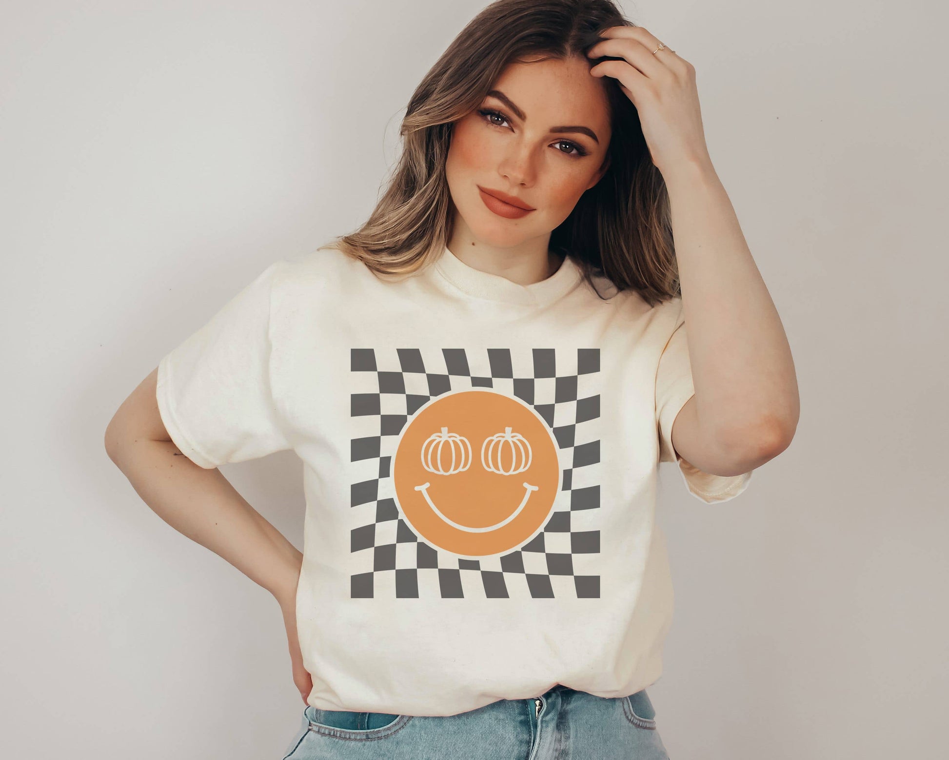 Checker Pumpkin Smiley Graphic Tee featuring a soft and comfortable unisex fit. Perfect for versatile styling like rolling up the sleeves, tying a side knot, or lounging around.