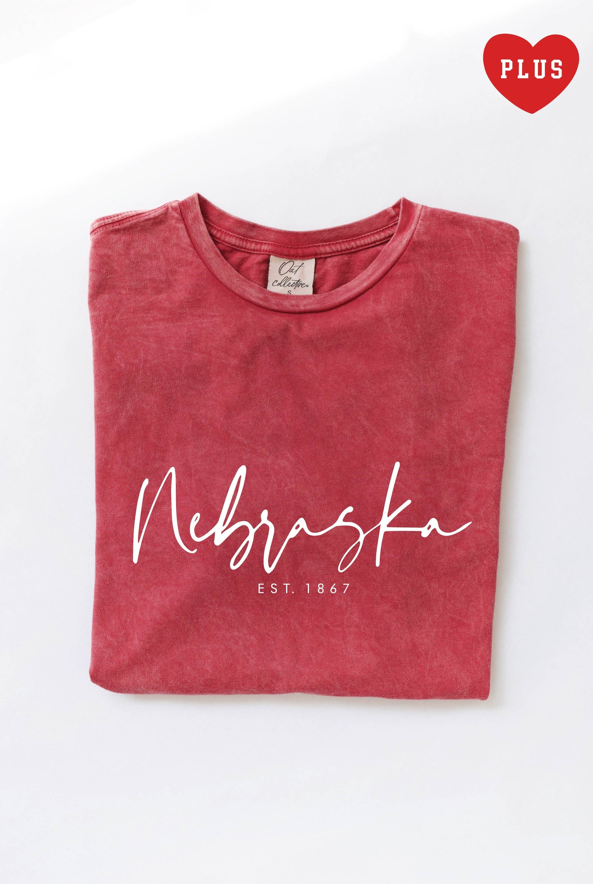 NEBRASKA EST. 1867 Graphic Plus Size Mineral Washed Top in cardinal red. Made from 100% premium cotton jersey, featuring a relaxed fit and screen printed design with water-based ink. Each top is uniquely dyed, offering a distinctive look.