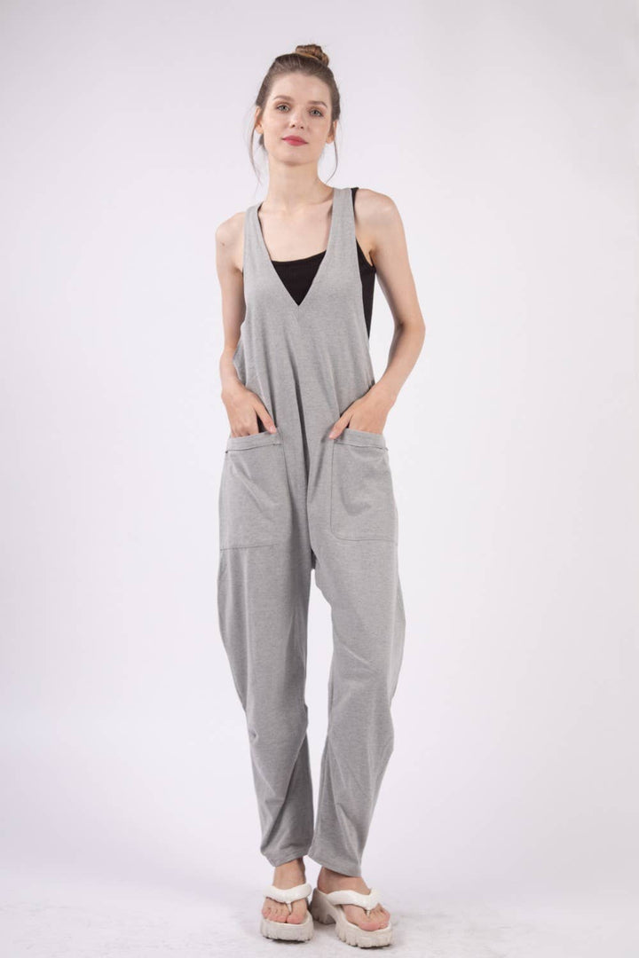 Casual loose fit solid knit baggy jumpsuit with a deep V-neck, sleeveless design, raw edge detail, and side pockets. 