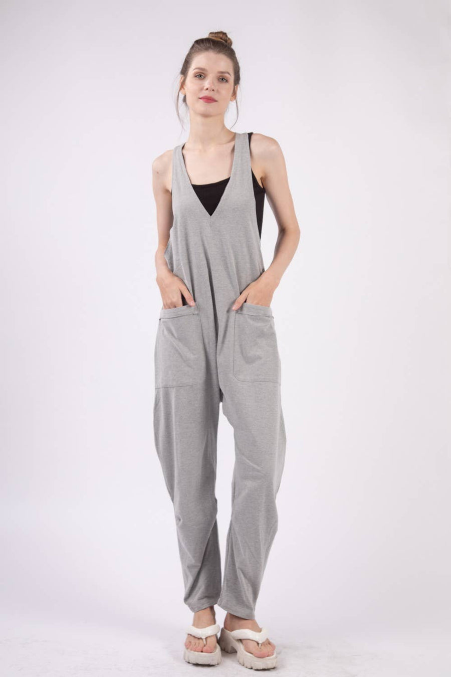 Casual loose fit solid knit baggy jumpsuit with a deep V-neck, sleeveless design, raw edge detail, and side pockets. 